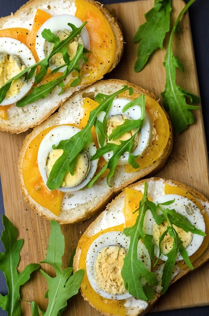 Sandwiches met gekookte eieren, gele tomaten en rucola.