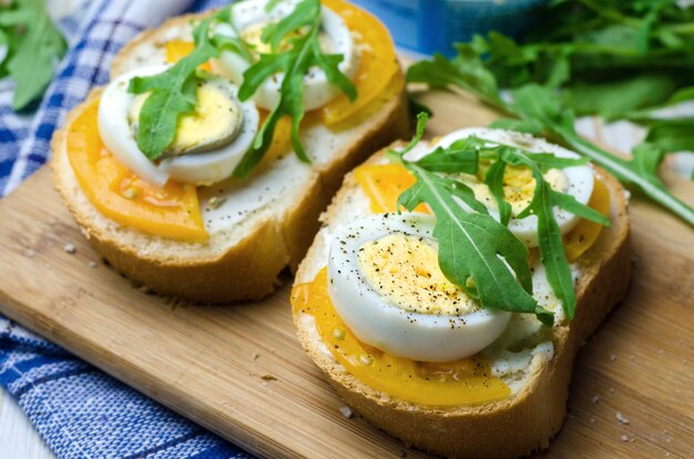 Sandwiches met gekookte eieren, gele tomaten en rucola.