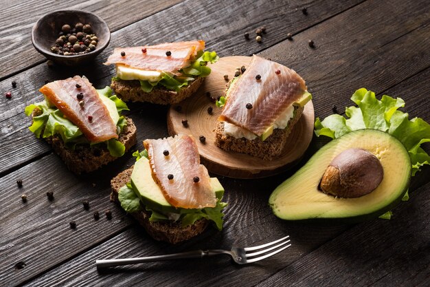 Sandwiches met gerookte vis en avocado op een bord op een donkere achtergrond