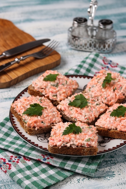 Sandwiches met krabstokken en wortelen op een plaat op een blauwe achtergrond