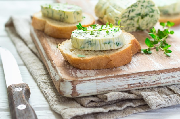 Sandwiches met kruidenboter op snijplank op witte houten achtergrond.