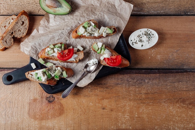 Sandwiches met pastaavocado tomaat Volkoren brood Veganistische sandwich van groenten op zwarte snijplank Houten achtergrond