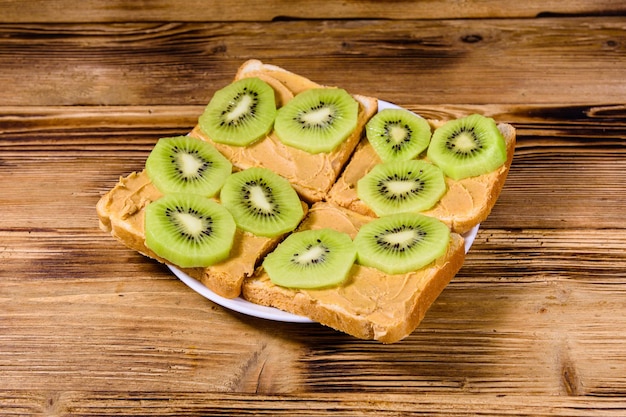 Sandwiches met pindakaas en gesneden kiwi's in plaat op een houten tafel