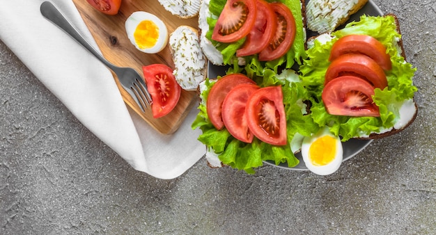 Foto sandwiches met tomaten, roomkaas, sla en gekookte eieren voor een gezonde lunch
