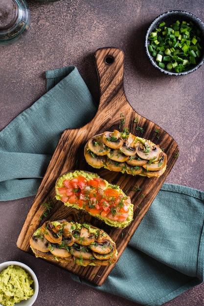 Sandwiches on rye bread with guacamole fried mushrooms tomatoes and dill top and vertical view