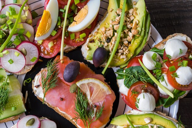 Sandwiches or tapas with bread , cream cheese, vegetable and tasty toppings. 