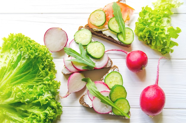 Sandwiches van tarwe bruin brood met komkommers en radijs met bladeren van verse groene salade