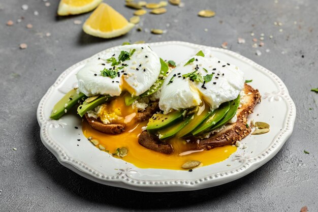 Sandwiches with avocado Poached Eggs sliced avocado and egg on toasted bread for healthy breakfast or snack Healthy fats clean eating for weight loss top view