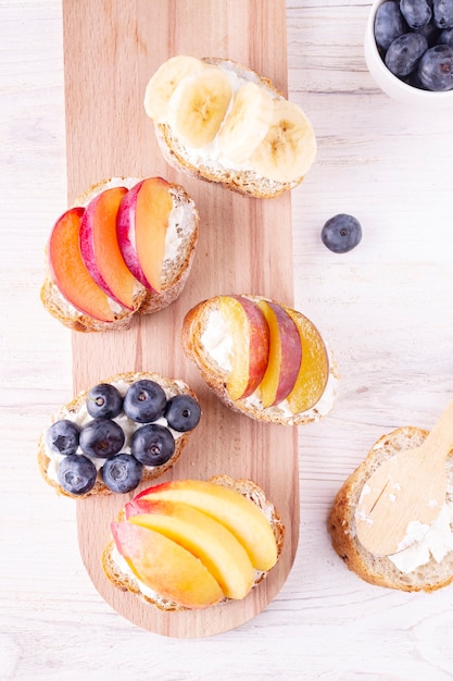 Sandwiches with berries and fruits on a wooden board