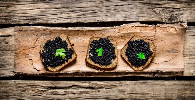 Sandwiches with black caviar and greens . On a wooden table. Top view