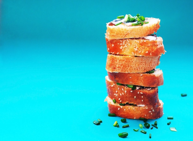 Sandwiches with butter and little salted fish for healthy snack on turquoise background