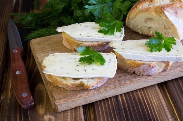 Sandwiches with cheese and herbs on the brown cutting board