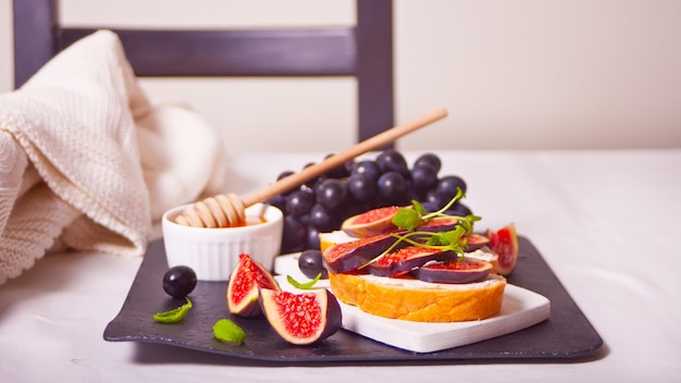 Sandwiches with cream cheese, figs and honey on the black tray