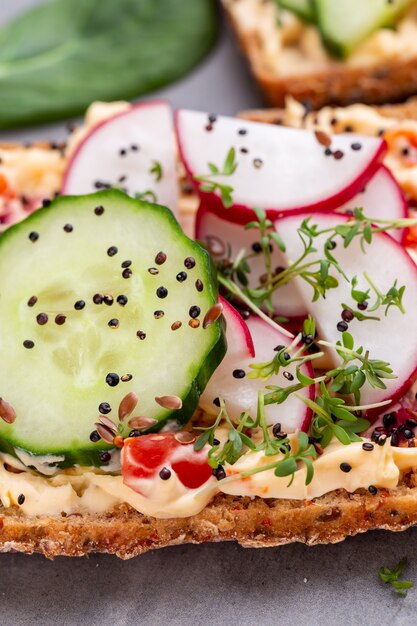 Sandwiches with cream cheese, vegetables and salami. Sandwiches with cucumber, radish, tomatoes, salami on a gray surface, top view. Flat lay.