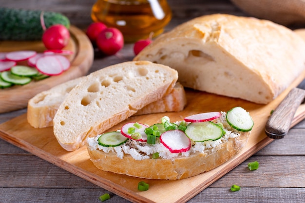 Sandwiches with cucumbers, radishes and cream cheese on wooden board, Closeup, Breakfast or lunch concept