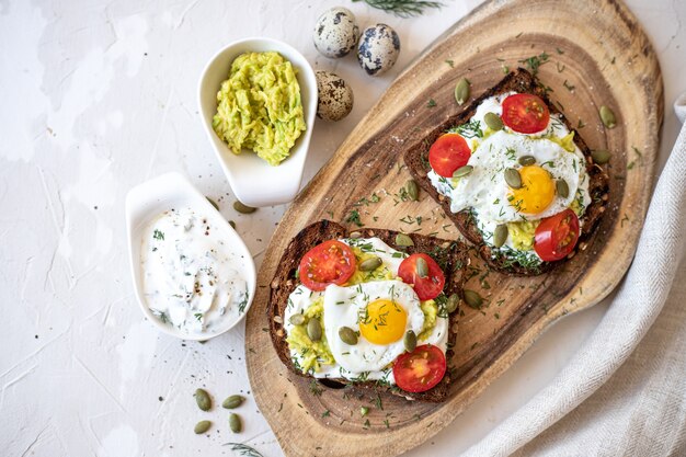 Sandwiches with fried quail eggs, on a wooden board. Top view