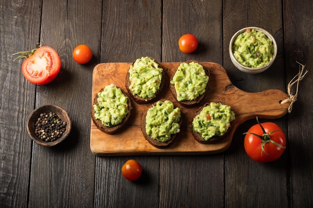 Sandwiches with guacamole sauce on a cutting board over old wooden background