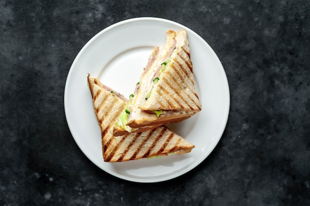 sandwiches with ham, cheese, tomatoes, lettuce and toasted bread in a white plate