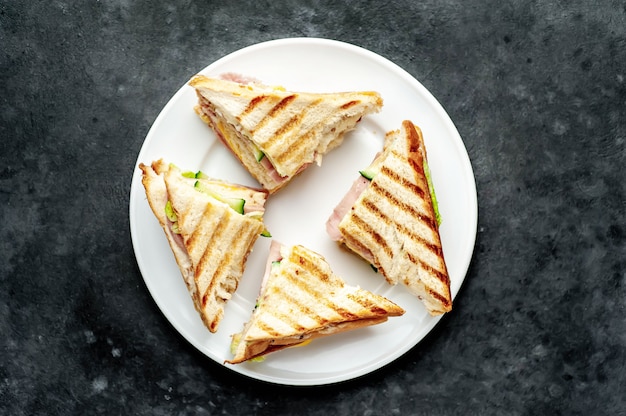 sandwiches with ham, cheese, tomatoes, lettuce and toasted bread in a white plate