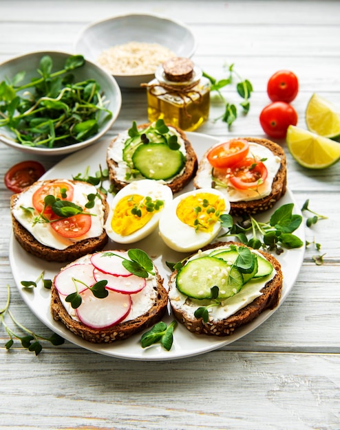 Photo sandwiches with healthy vegetables and micro greens on a wooden table