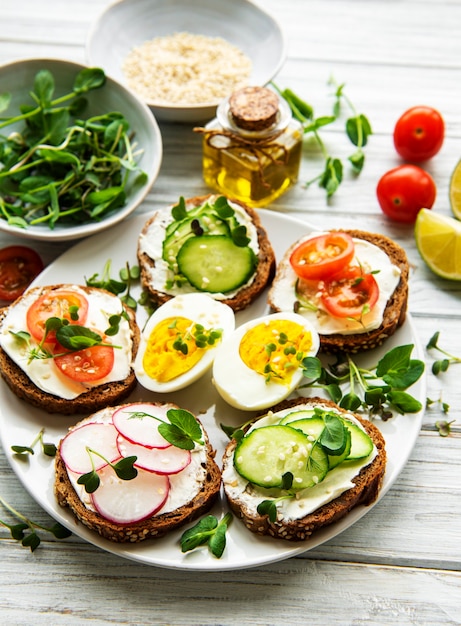 Sandwiches with healthy vegetables and micro greens on a wooden table