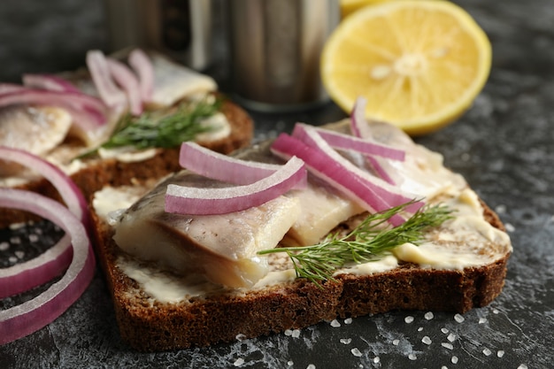 Sandwiches with herring fish on black smokey