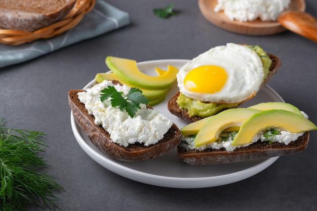 Sandwiches with a minced curd avocado fried eggs and herbs on the natural wooden cutting board