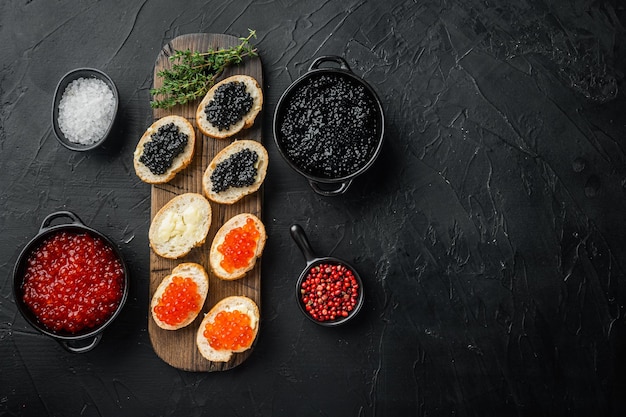 Sandwiches with red and black caviar baguette, on black background, top view flat lay with copy space for text