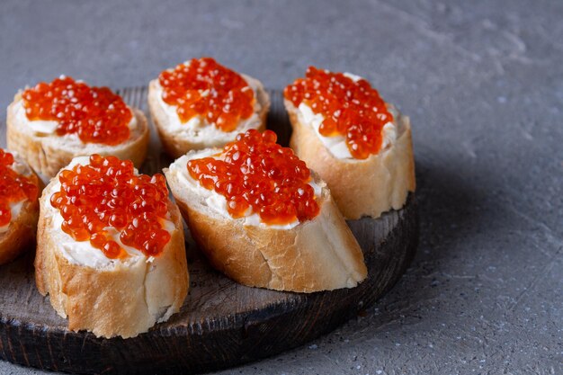 Sandwiches with red caviar on a round wooden board, copy space