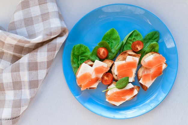 Sandwiches with red fish on a blue plate. decorated with greens