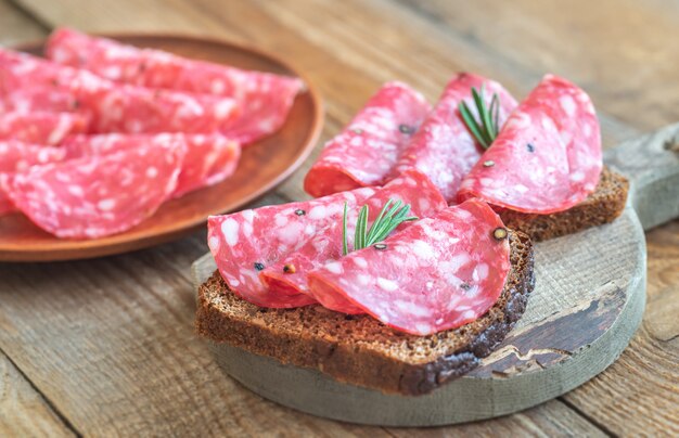 Sandwiches with salami on wooden board