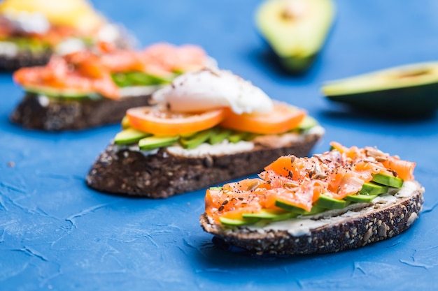 Sandwiches with smoked salmon and avocado on blue background. Concept for healthy nutrition.
