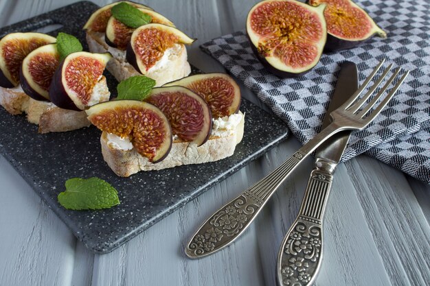 Sandwiches with soft cheese and figs on the grey wooden background