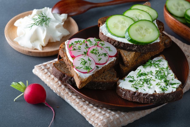 Sandwiches with soft cheese radish and cucumber on a wooden cutting Board Healthy breakfast