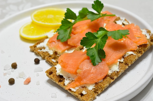 sandwiches with soft cheese and salmon slices decorated with parsley and lemon slices