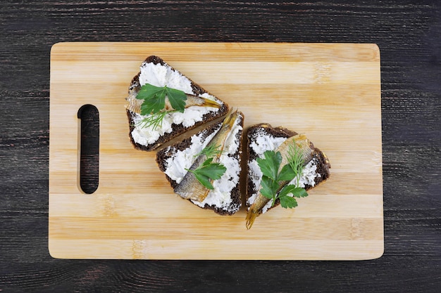 sandwiches with sprats on wooden Board