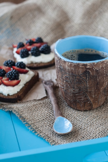 Sandwiches with sweet cheese and berries, a cup of coffee