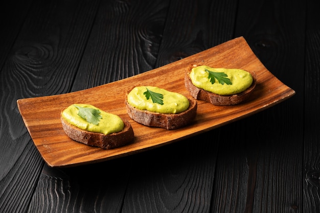 Sandwiches with toasted bread and squash caviar with parsley on a wooden background