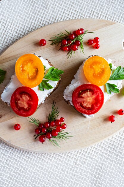 Sandwiches with tomato and herbs and berries on a wooden plate