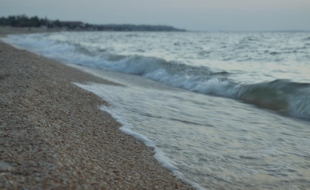 日没のぼやけた背景でアゾフ海の砂浜の海岸