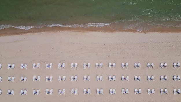 A sandy beach stretches along the seaside adorned with empty sun loungers Aerial view