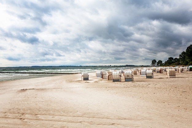 Sandy beach with beach chairs. Late summer landscape with cloudy sky. Vacation background. Baltic sea coast, travel destination