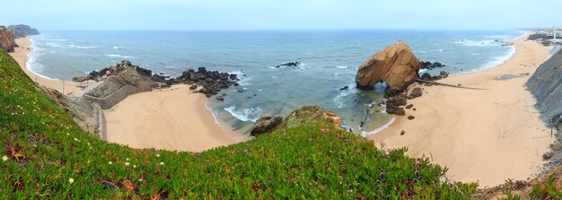 Sandy beaches Praia do Guincho and Praia de Santa Cruz Portugal Misty weather People are unrecognizable Three shots stitch panorama Beautiful natural summer vacation travel concept