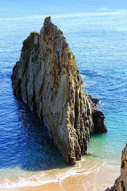 Песчаный пляж Мексота и остроконечная скала (Испания). Ландшафт береговой линии Атлантического океана.