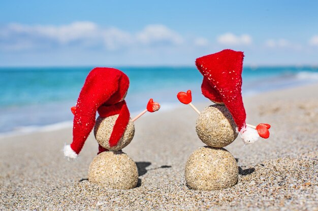 Photo sandy snowmen on the beach new years holiday in hot countries concept