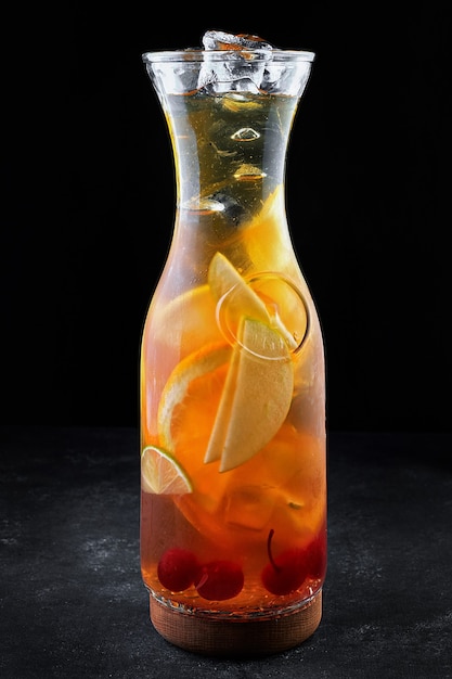 Sangria in a transparent jug with ice, on a black table