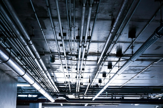 Sanitaire systeemleidingen en elektrische kabels geïnstalleerd onder gewapend beton met vlakke plaat in gebouwVentilatieleidingen in ondergrondse parkeergarage