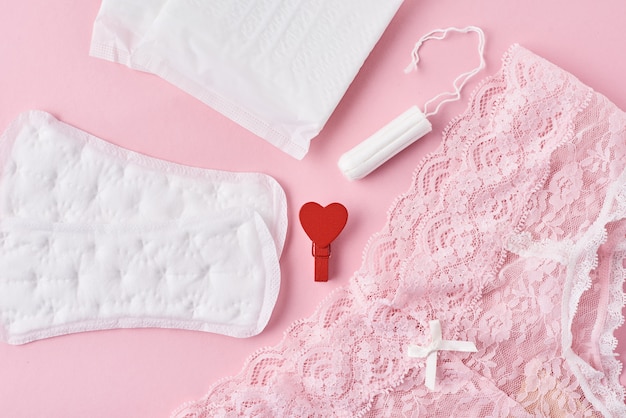 Гигиеническая прокладка, менструальная чашка, тампон и трусики на розовом