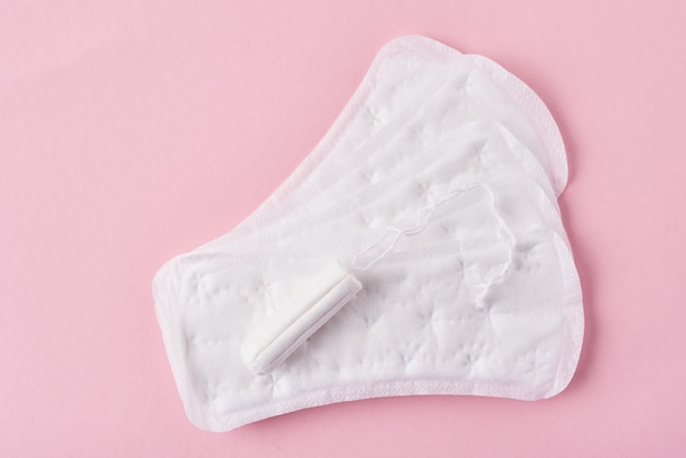 Sanitary pad and menstrual tampon on a pink background