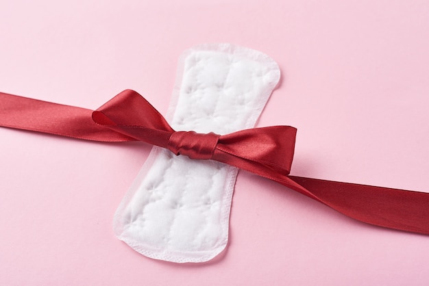 Photo sanitary pad and red ribbon on a pink background